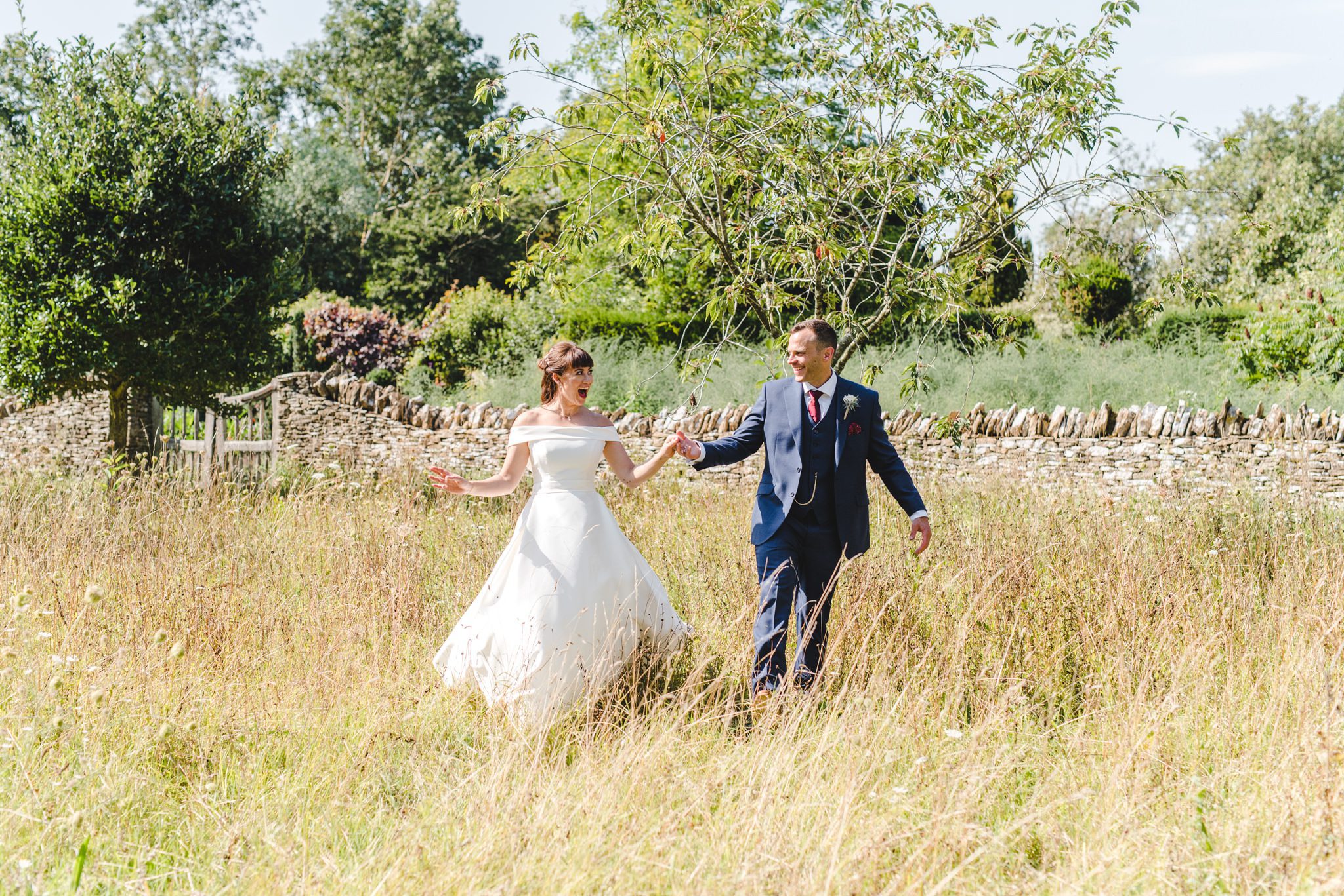 Bride and groom walking through a meadow