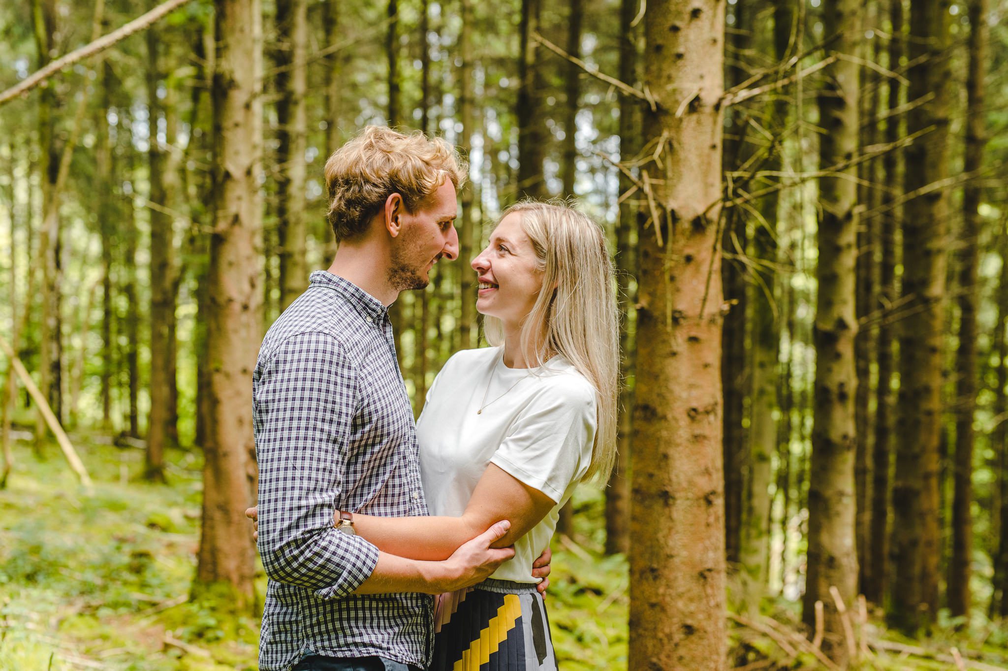 A couple whose wedding was postponed by Coronavirus looking at each other in the woods