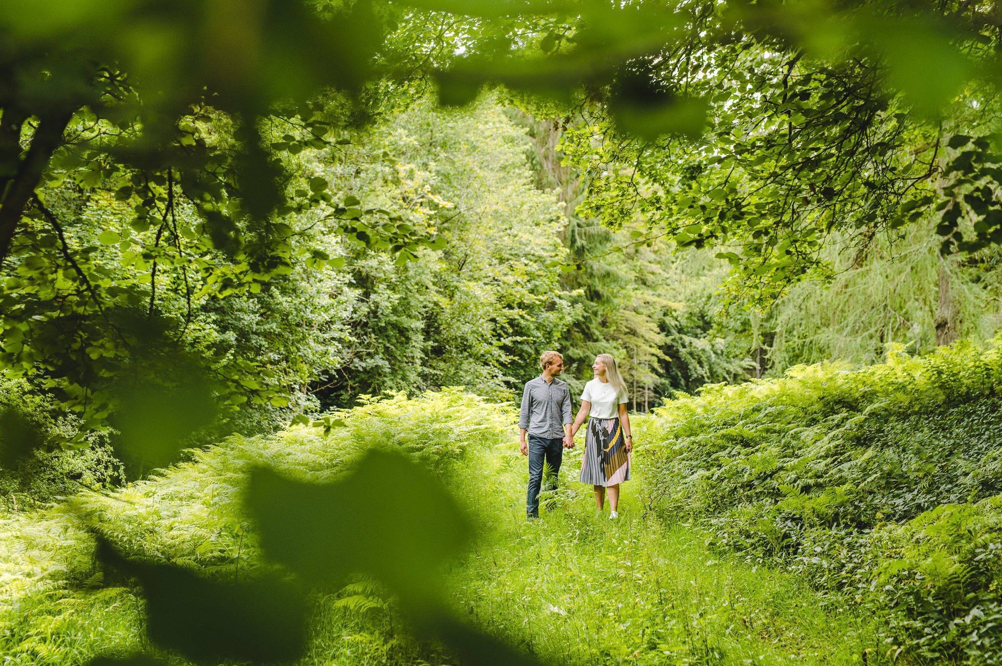 An engaged couple walking in woodland