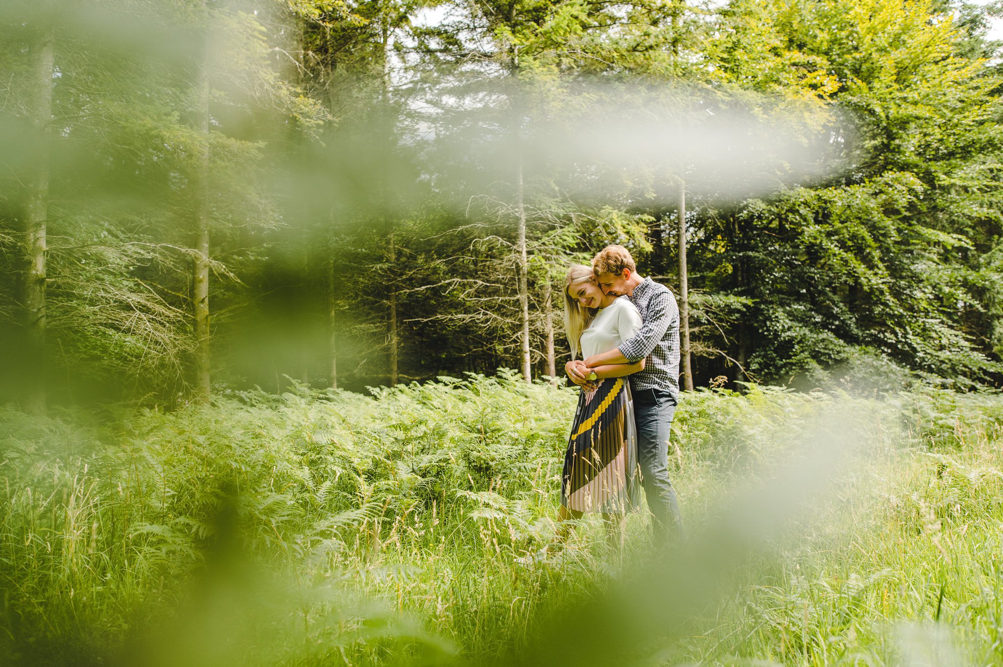 An engaged couple standing in the woods