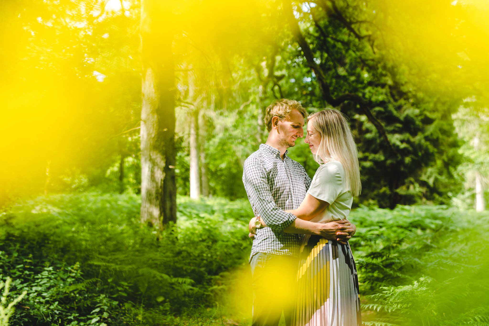 A yellowy pictures shot through flowers of a couple looking at each other