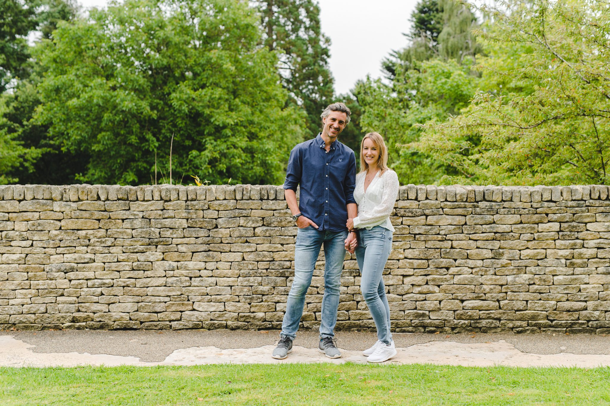 An engaged couple standing by a wall