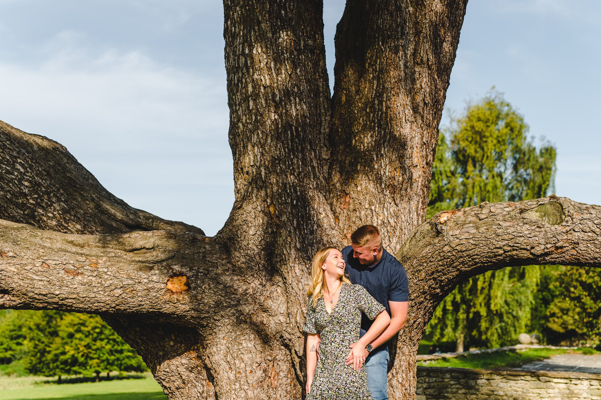 An engagement shoot couple in the sunlight by a big tree