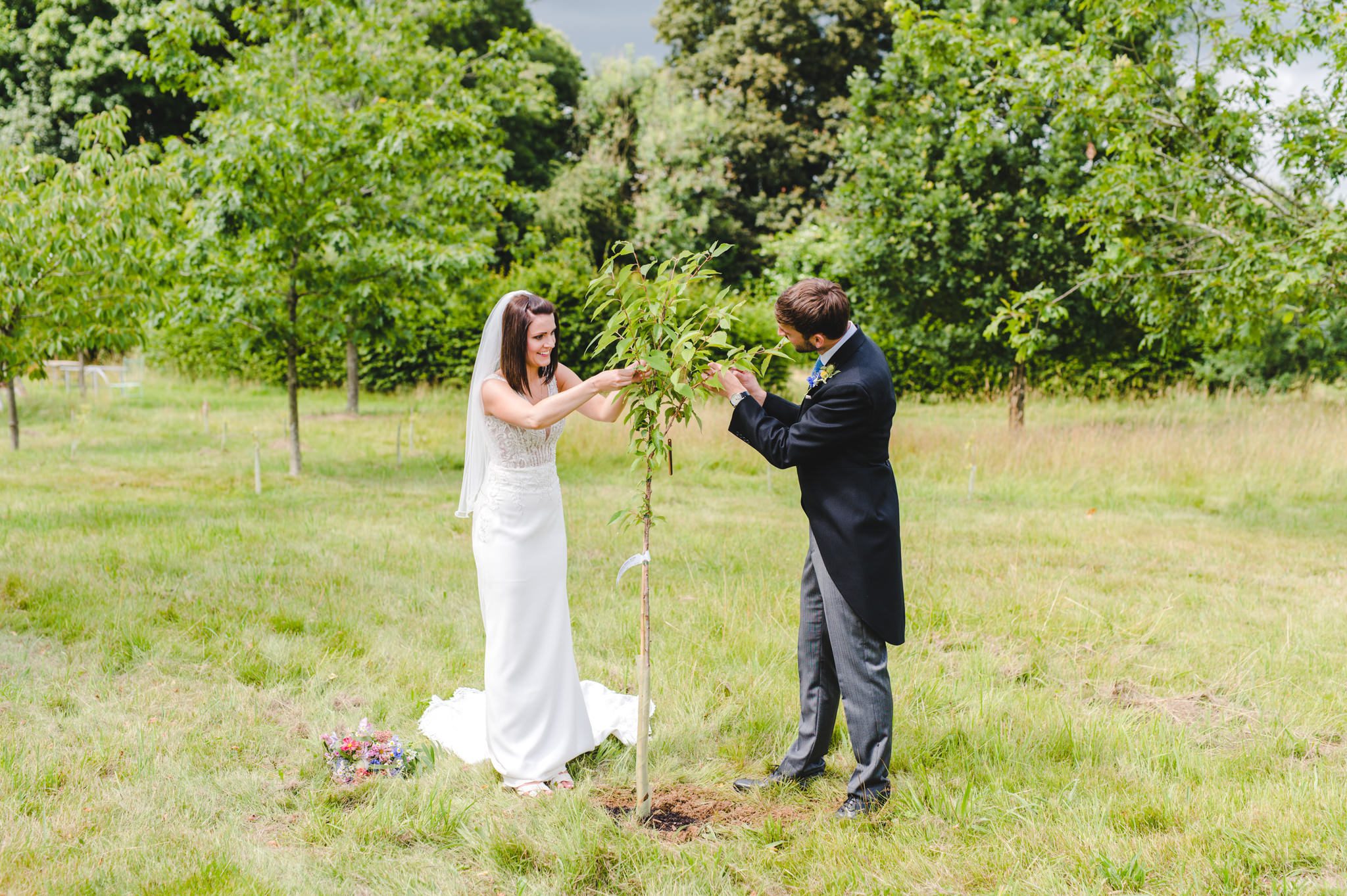 A bride and groom tying ribbons to a tree at Matara
