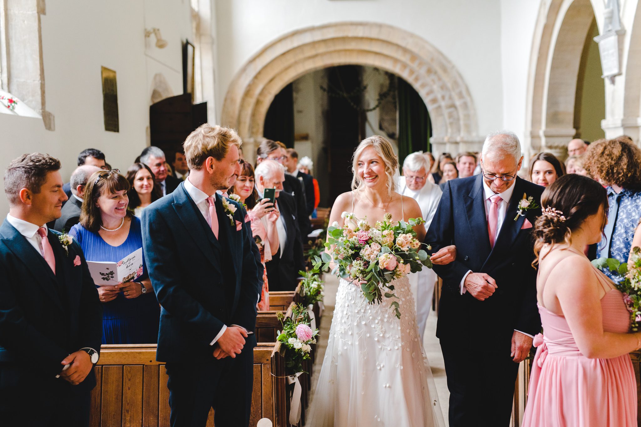 A bride arriving at the top of the aisle to meet her husband in Chedworth Church