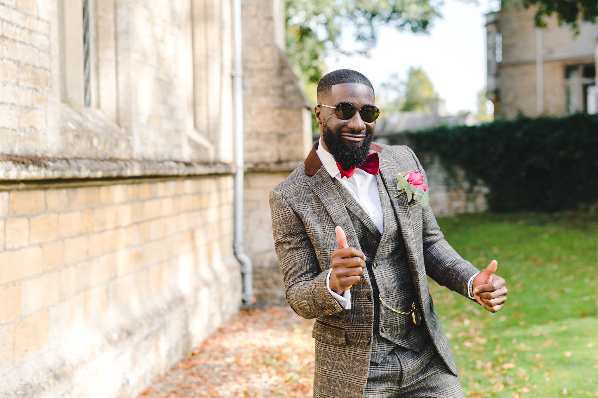 A groom striking a pose at Lower Slaughter Church