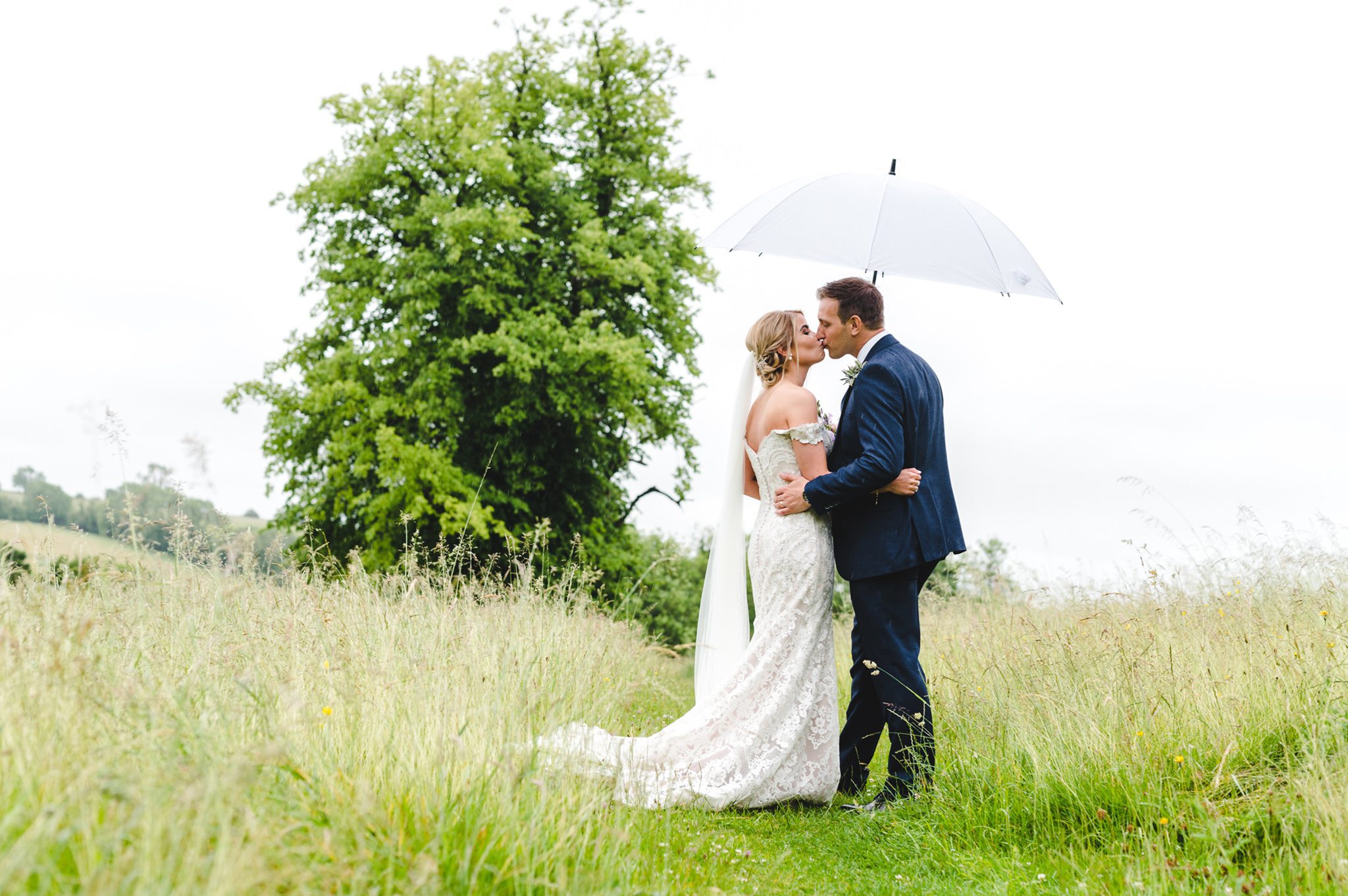 A bride and groom standing under an umbrella