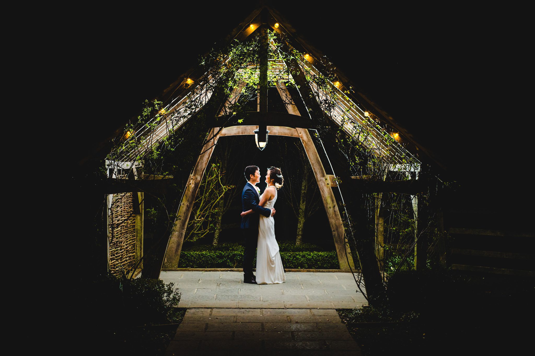 A couple standing under the arbor at Hyde House while the photographer takes a picture with off camera flash