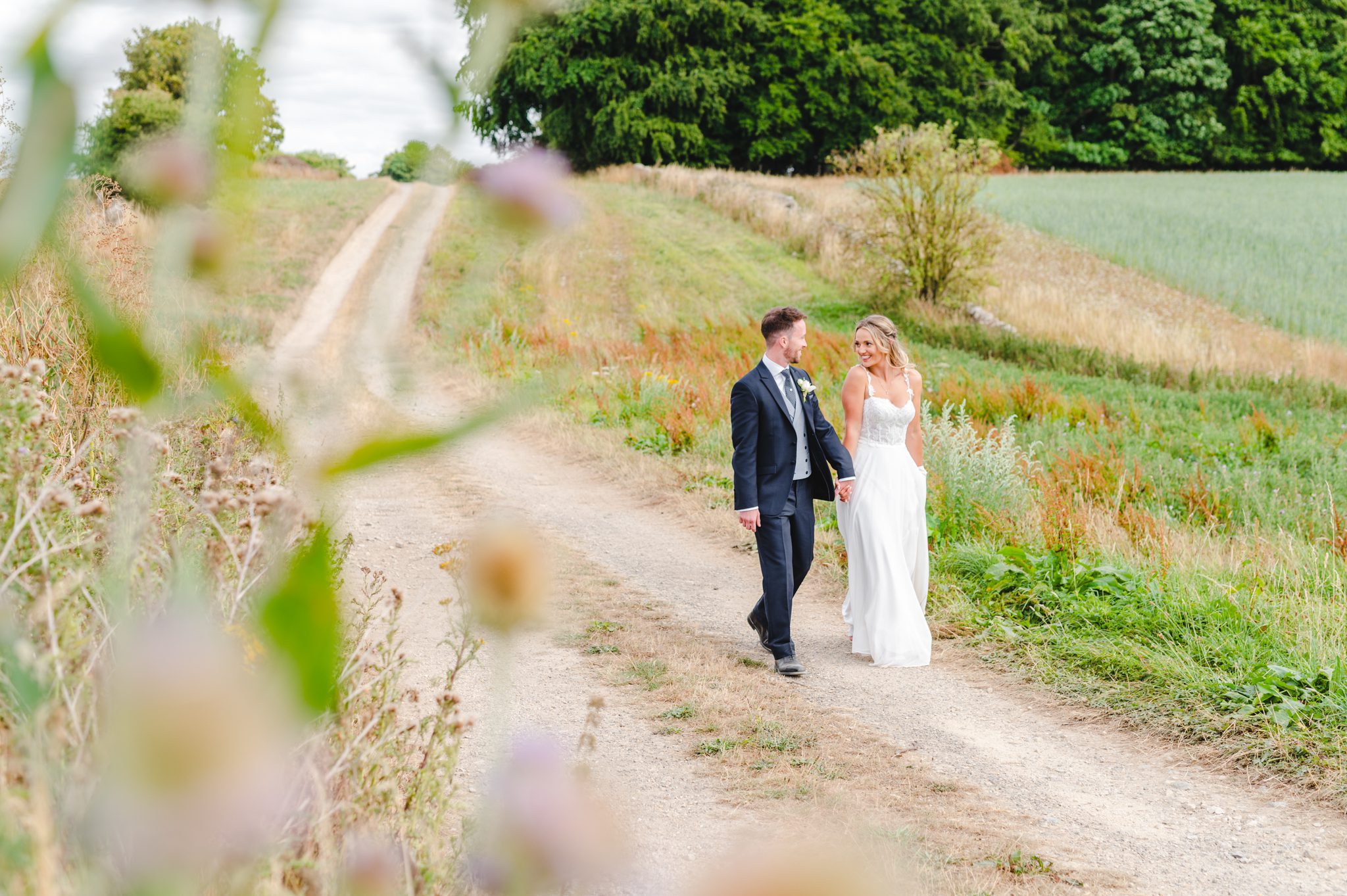 Bride and groom walking in the Cotswolds Countryside