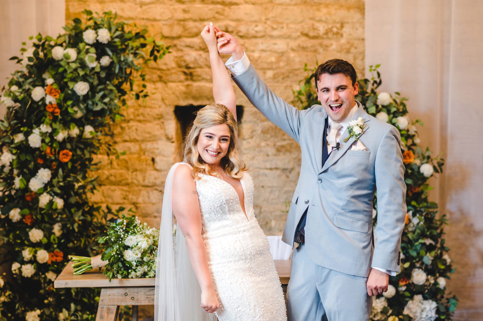 a just married couple celebrating with their arms in the air at lapstone barn