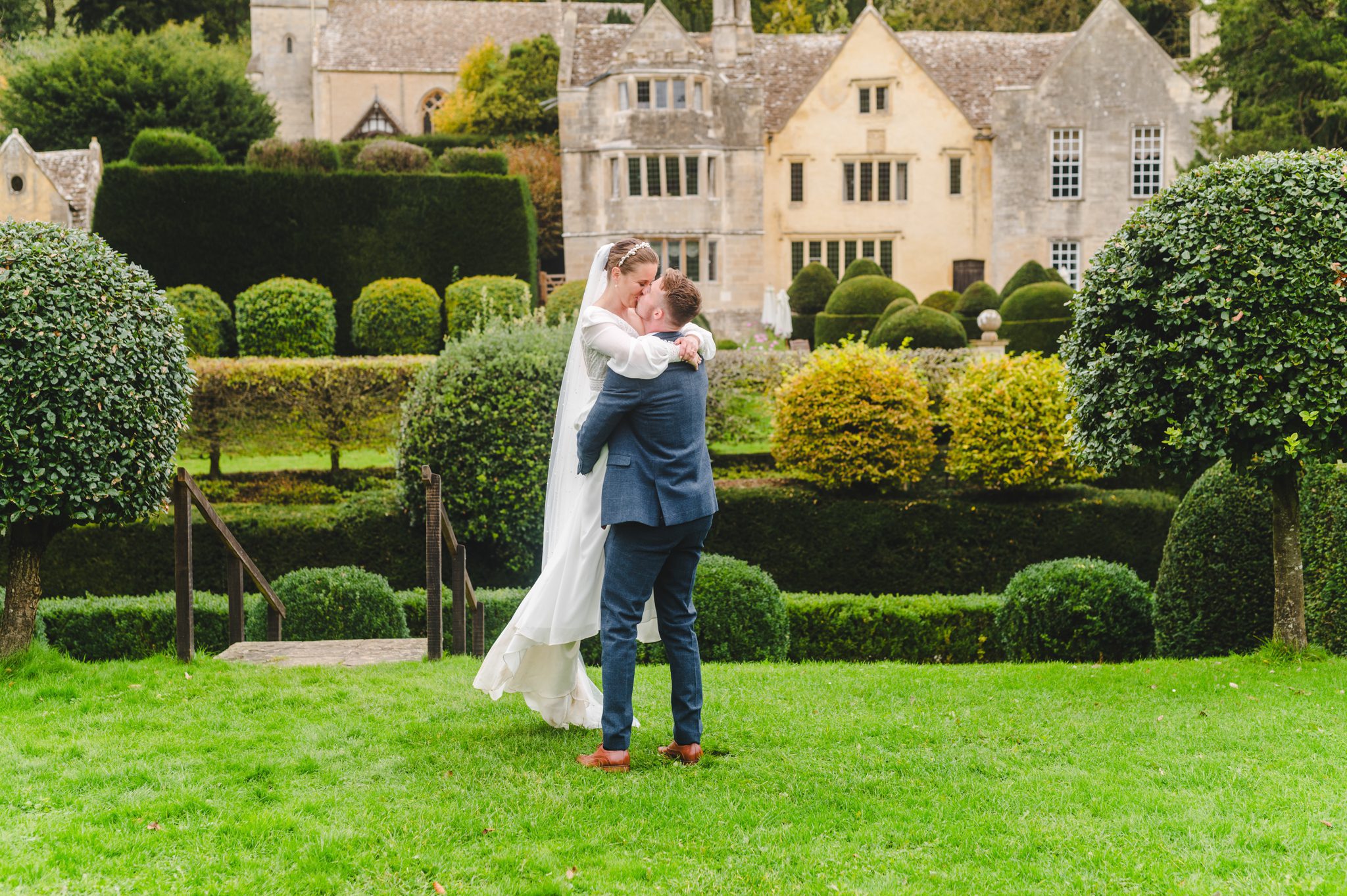 A newly married couple standing on from of the wedding venue Owlpen Manor