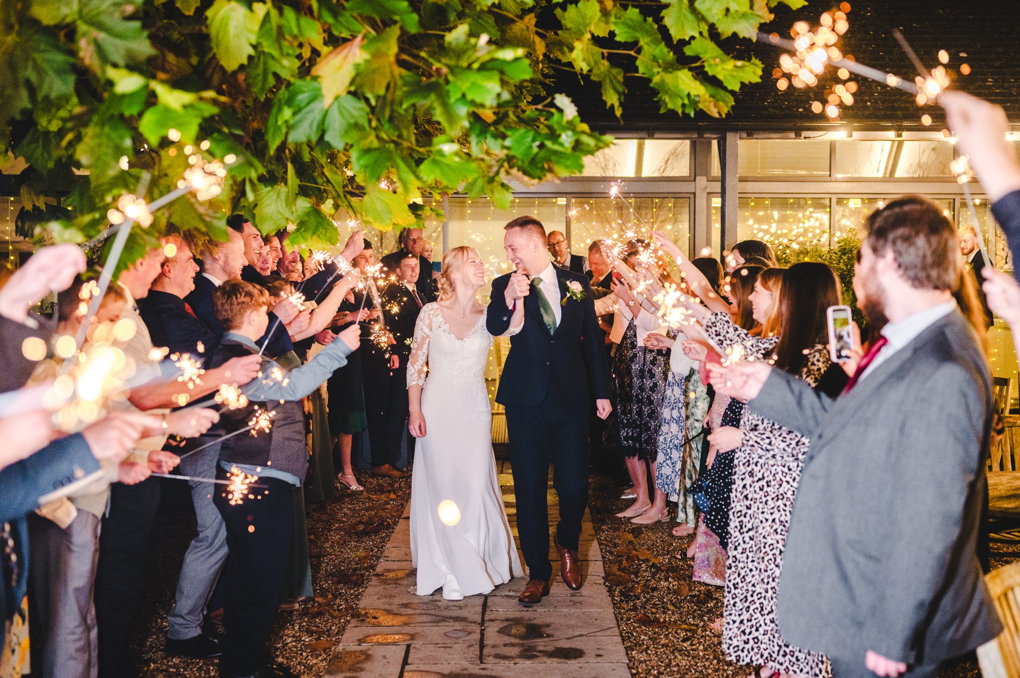 a man and woman holding sparklers and walking down a path at Lapstone Barn