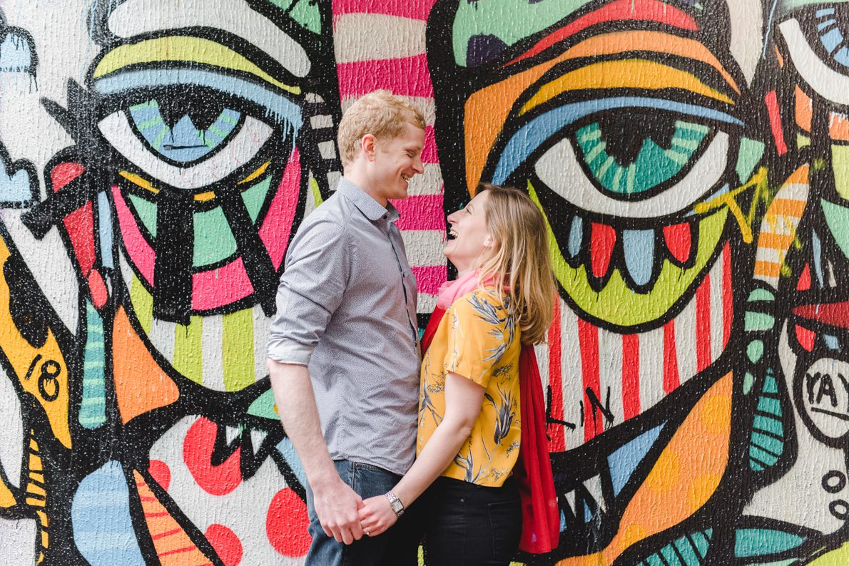 A couple stood in front of a graffiti backdrop