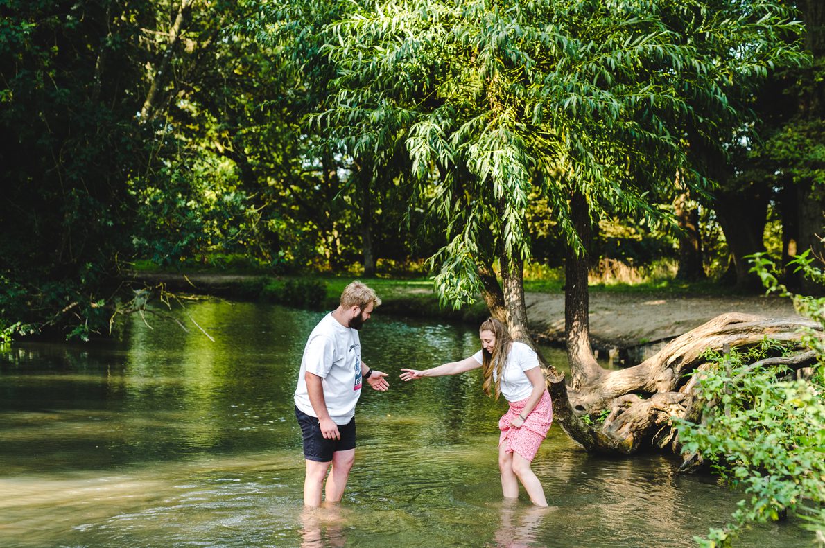 An engaged couple playing in a river