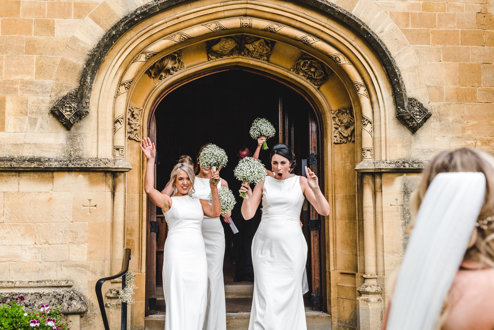 A group of bridesmaids in white dresses exiting the ceremony
