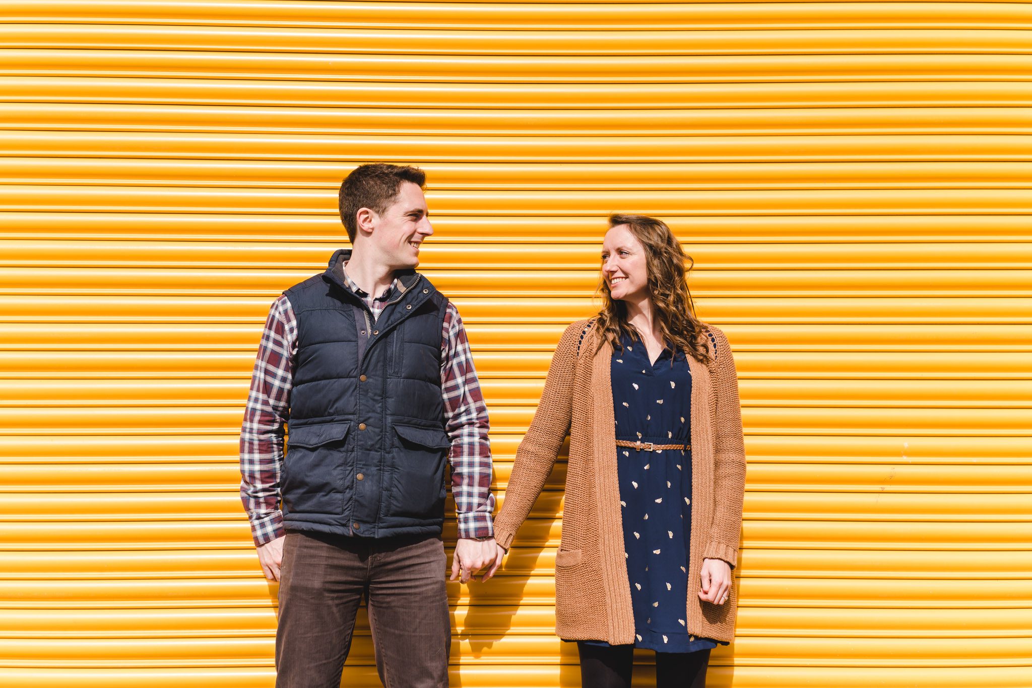 A couple standing against a yelow door