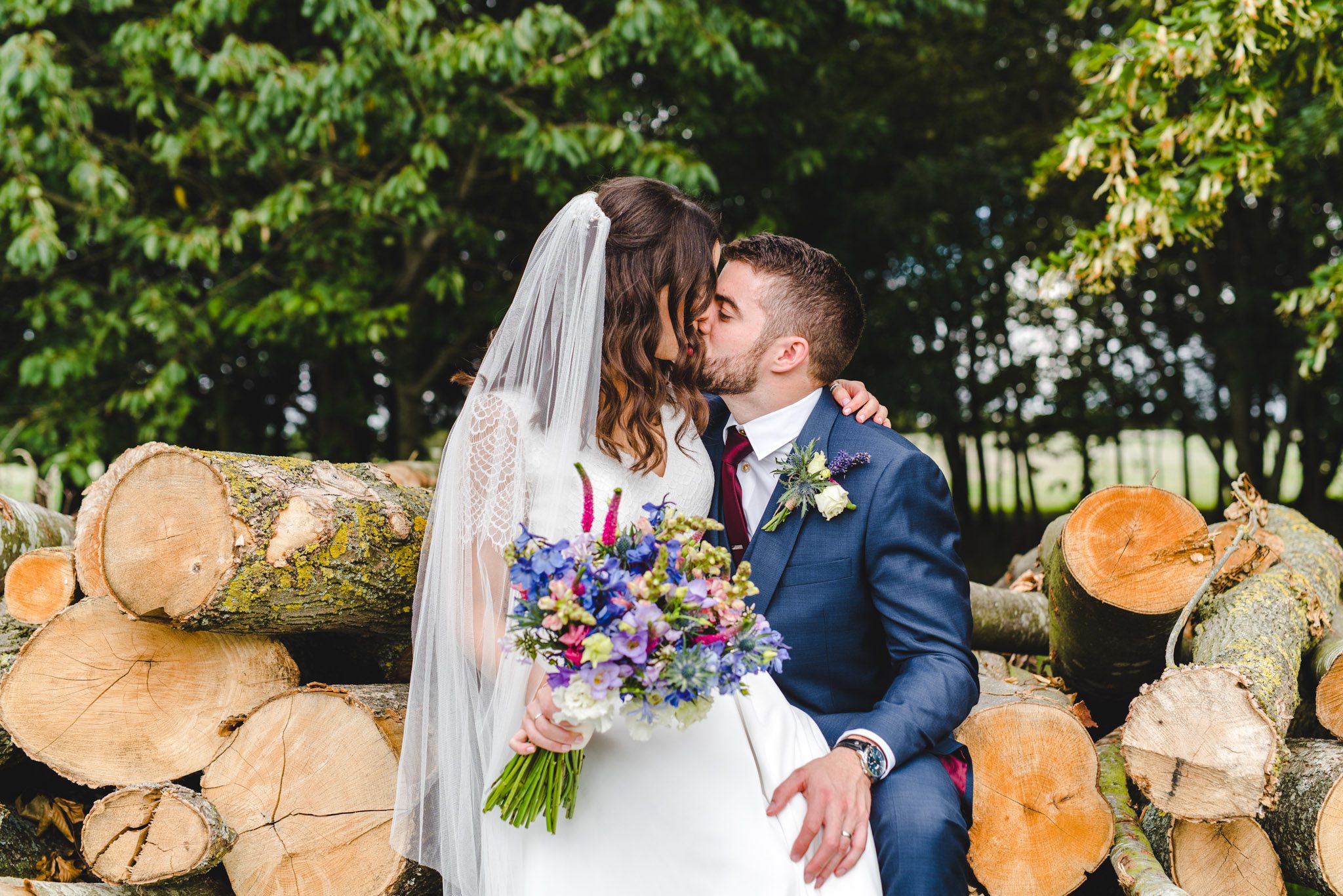 A bride and groom sat on a log planning their wedding day timeline