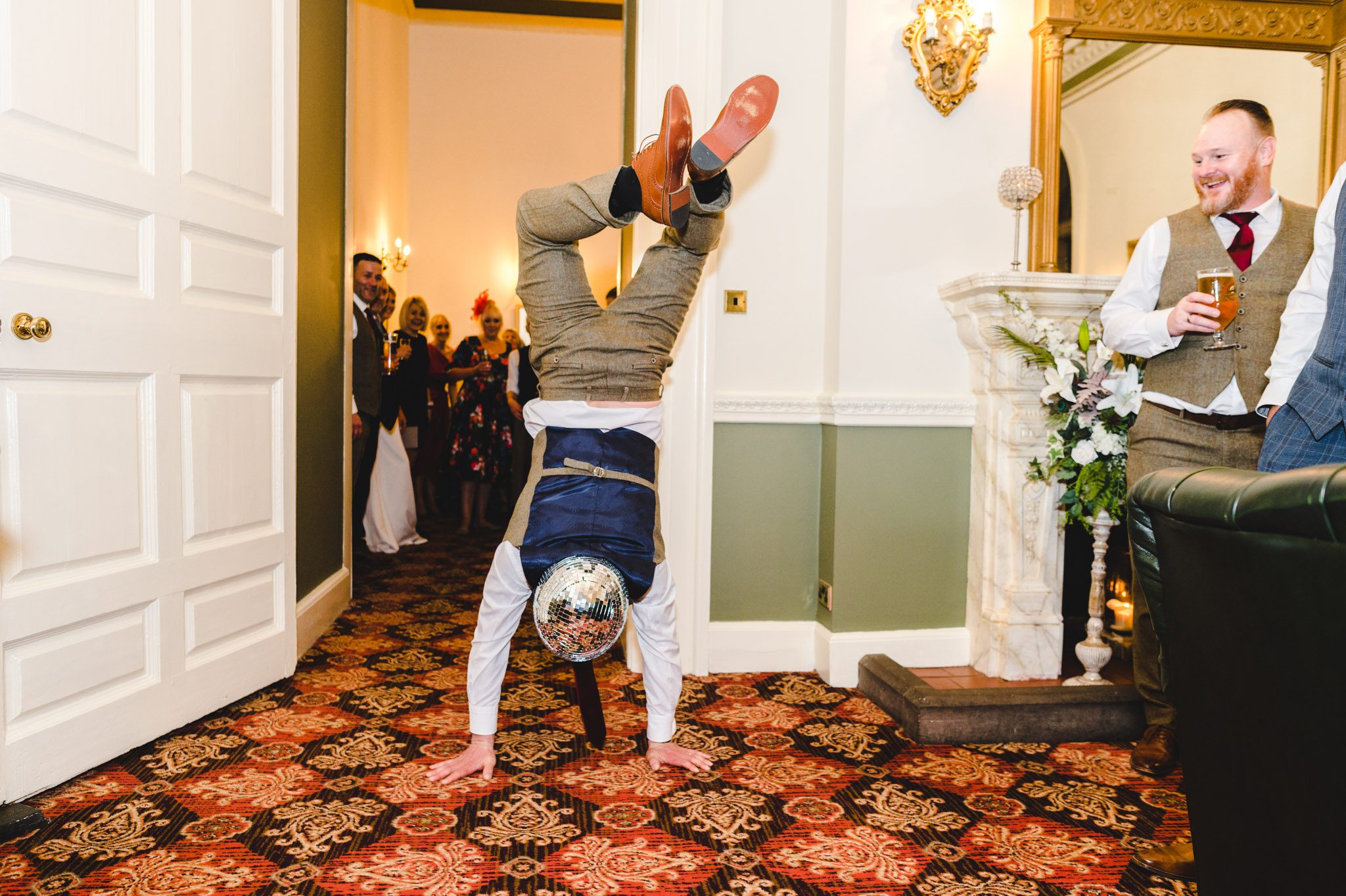 man doing a handstand with a disco ball hat on