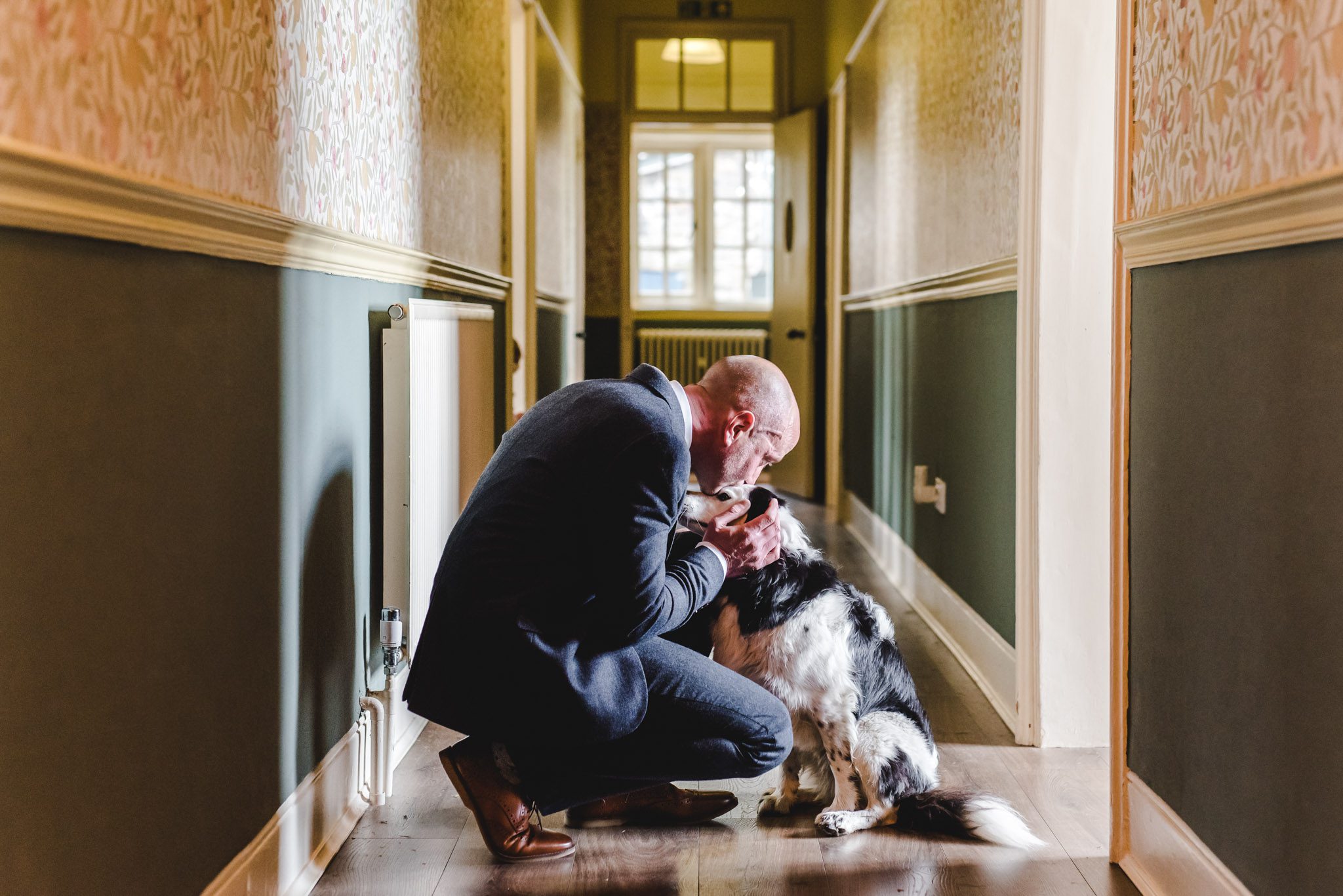 A man cuddling his dog in a hallway before he gets married