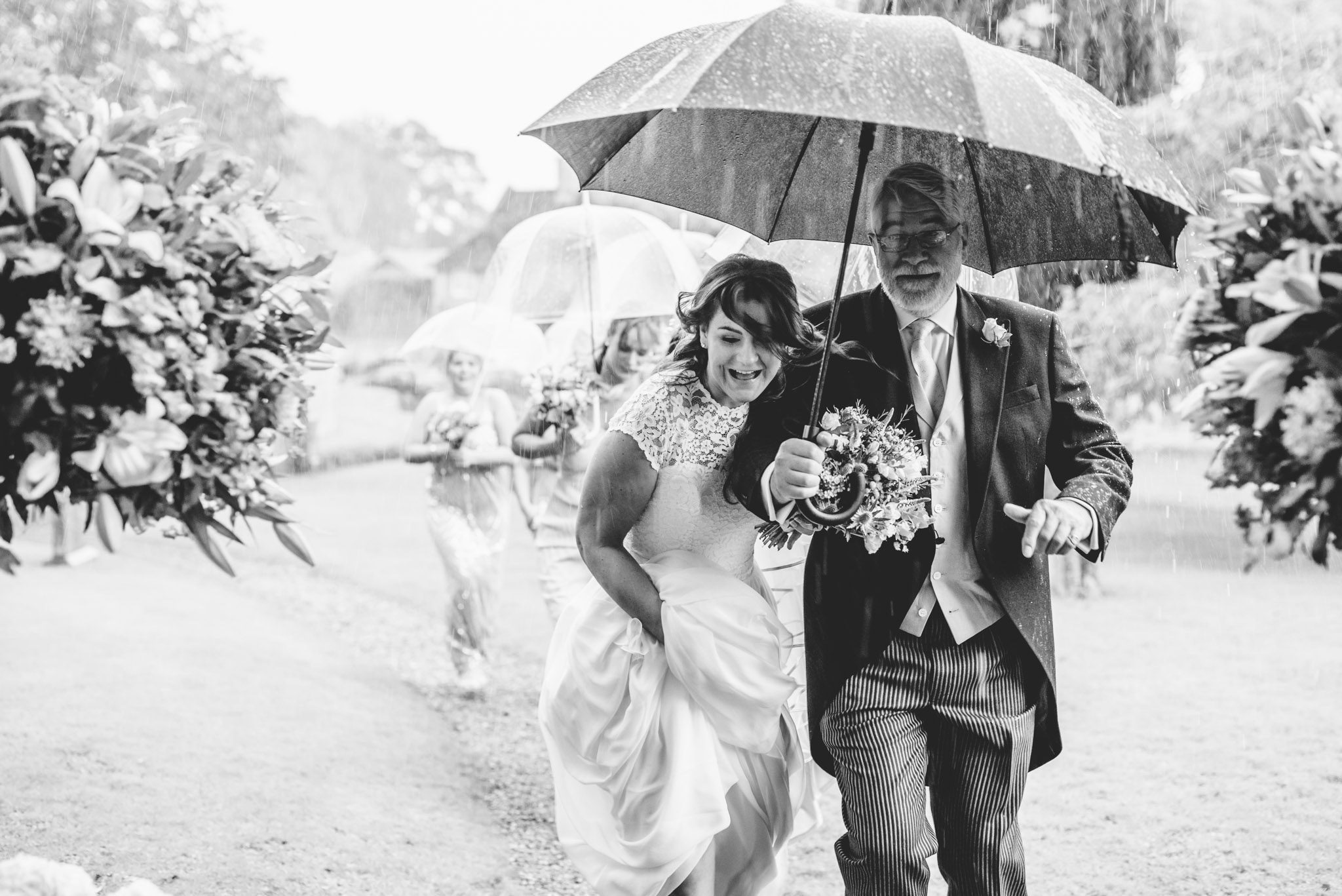 A bride and her father running through the rain to her wedding ceremony
