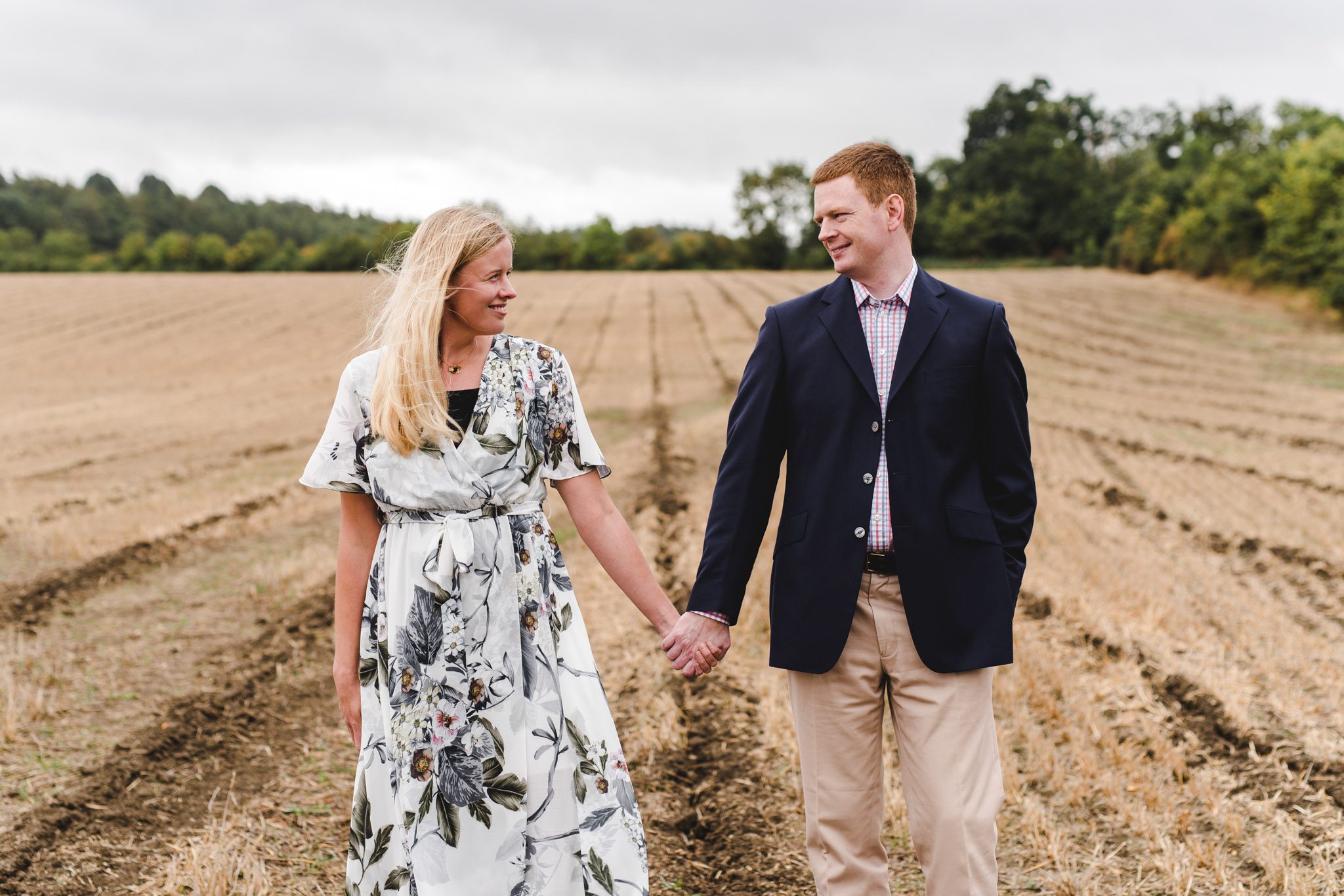 An engaged couple holding hands in a cornfield